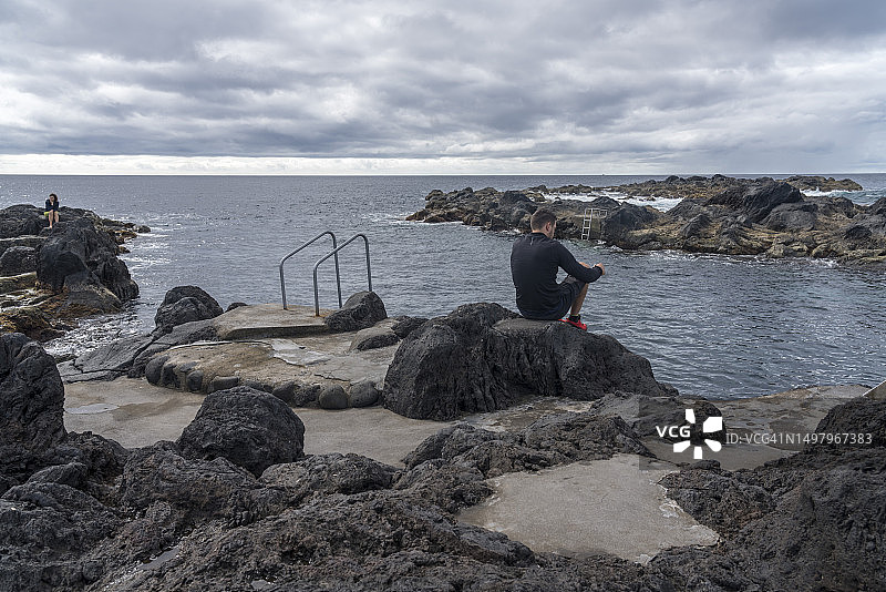 两人坐在亚速尔群岛圣米格尔岛海岸线附近图片素材