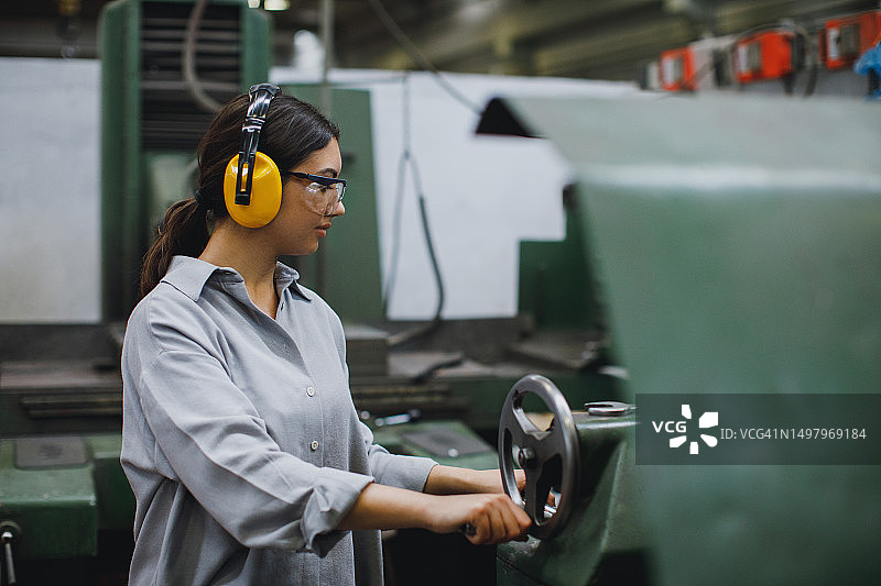 年轻女车床工在工厂操作铣床图片素材