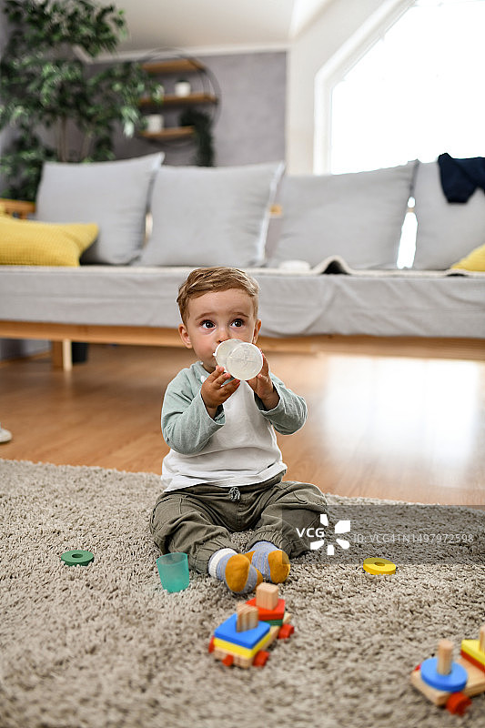 坐在地板上喝水的男婴图片素材
