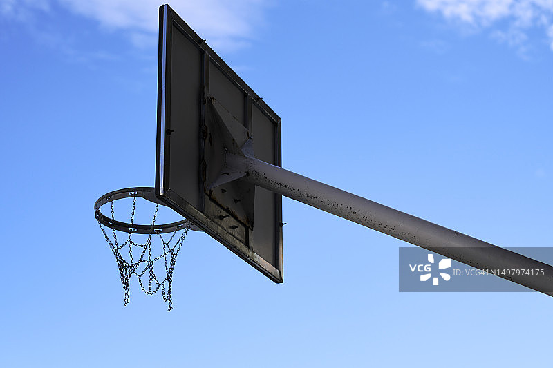 篮球架侧面，篮筐背景是交错的钢链，呈现蓝天白云图片素材