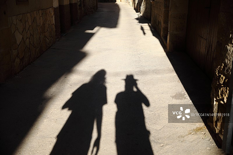 小巷中行走的两个男人的影子图片素材