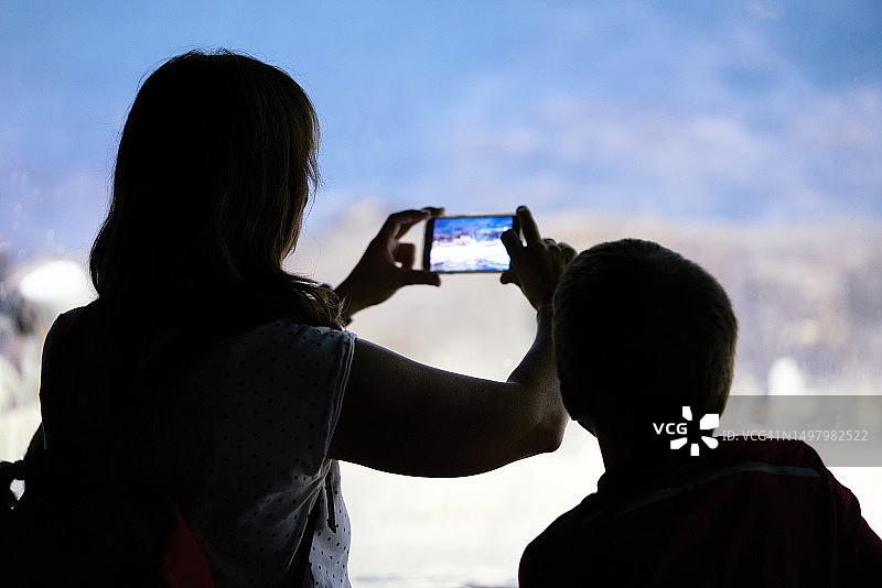 母子在水族馆里用手机拍照的背影图片素材