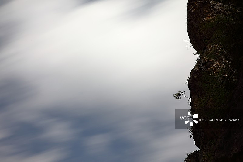 移动的云垂直悬崖和小树长曝光摄影图片素材