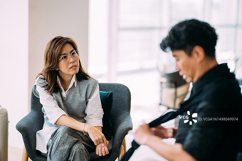 寻找解决方案：亚洲女心理学家和中年男人在现代办公室进行咨询治疗图片素材