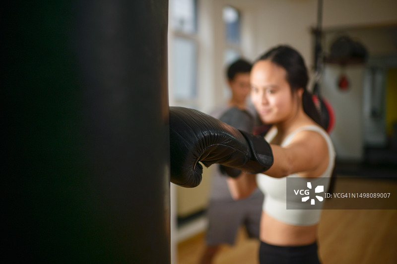 专注的年轻中国女子拳击手击打沙袋图片素材