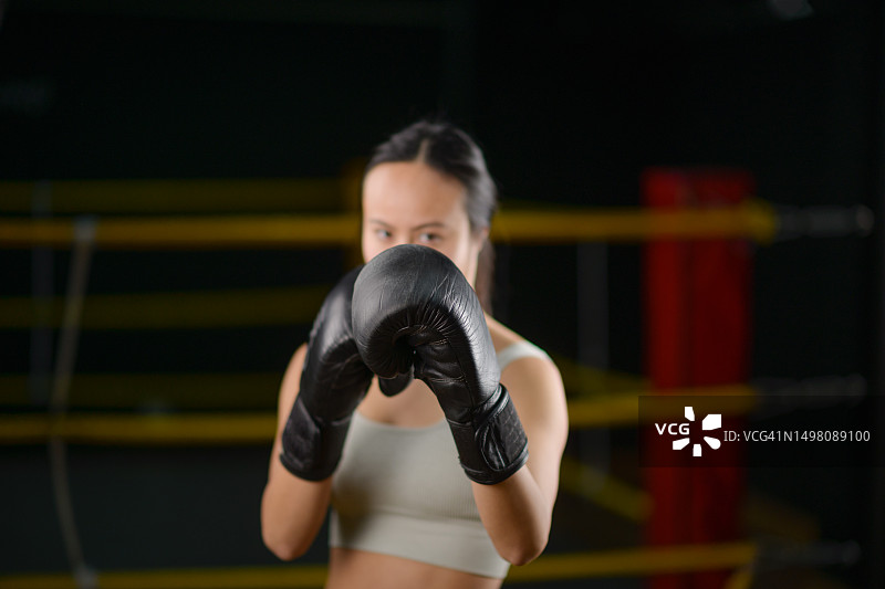 年轻的中国女子在拳击馆戴着拳击手套的肖像图片素材
