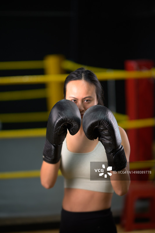 中国女运动员在拳击馆拳击台上戴拳击手套的肖像图片素材