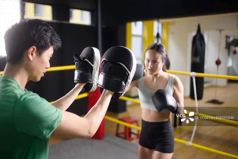 中国男女运动员在拳击练习中勾拳击打拳击台上的护垫图片素材