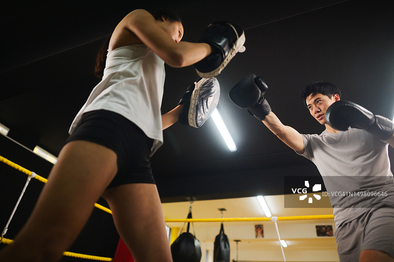 中国男女运动员在拳击台上勾拳和刺拳交叉训练的仰视角度图片素材