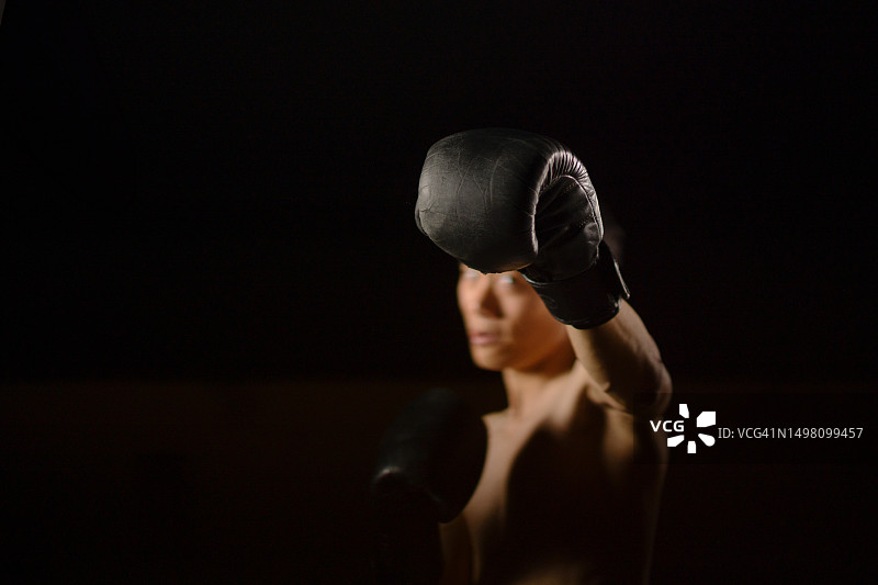 中国健壮男子拳击手在演播室进行影子拳击的低角度选择性聚焦拍摄图片素材