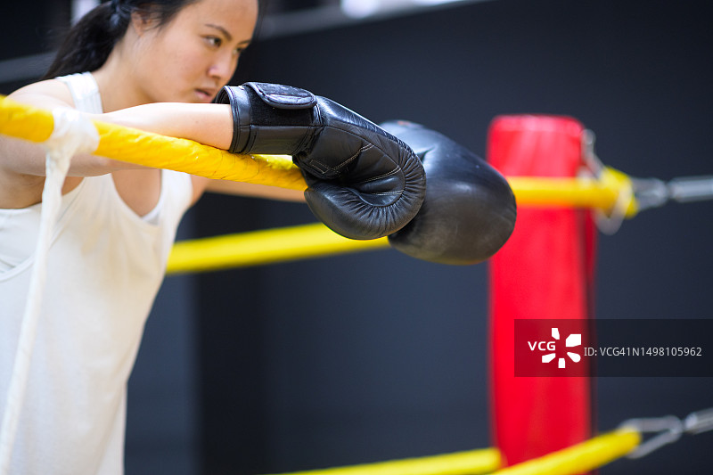 戴拳击手套的中国女人在拳击台上休息概念图图片素材