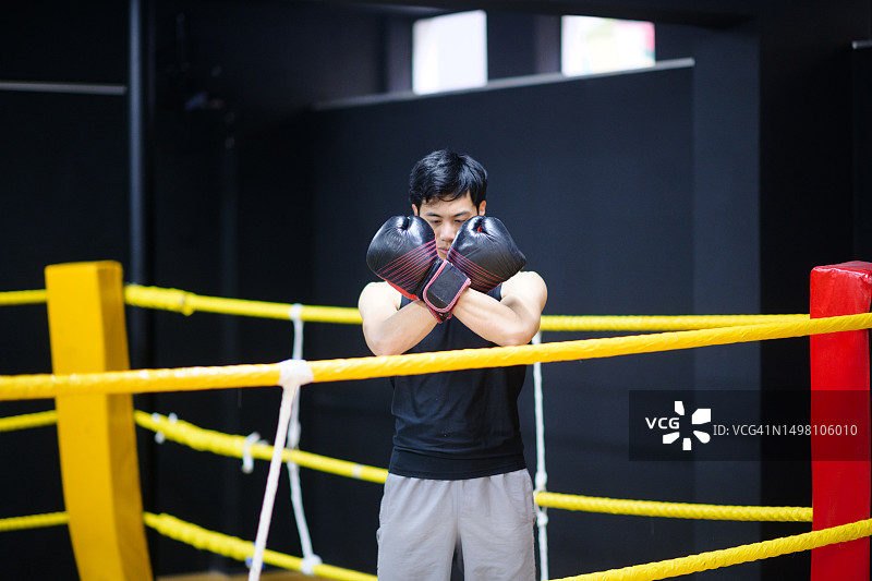 中国男性拳击手在拳击台上交叉双臂站立图片素材