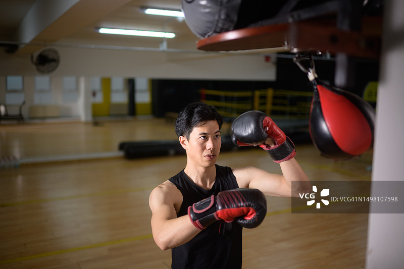在健身房练习速球拳击的亚洲男人图片素材