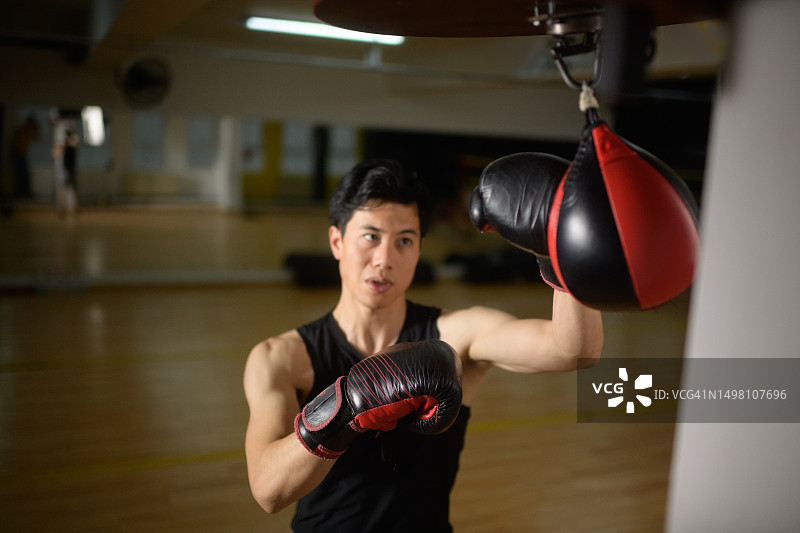 亚裔男子在健身房练习速度球拳击技巧图片素材