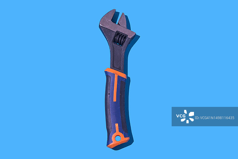 蓝色背景上的塑料柄金属扳手，工作、贸易和维修概念图片素材