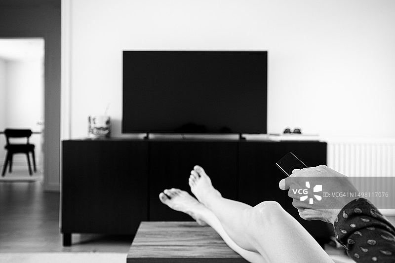 一名女子使用遥控器观看电视图片素材