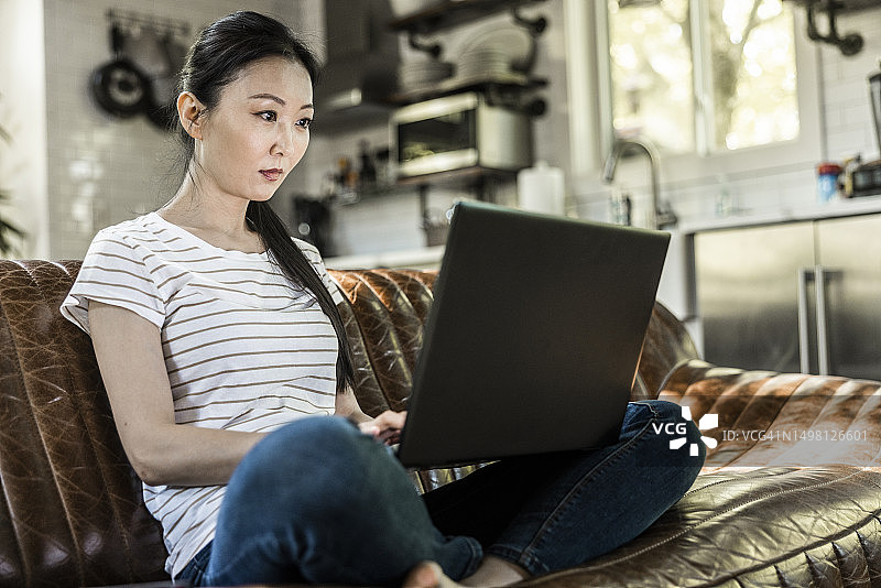 在度假屋沙发上使用笔记本电脑的女人图片素材