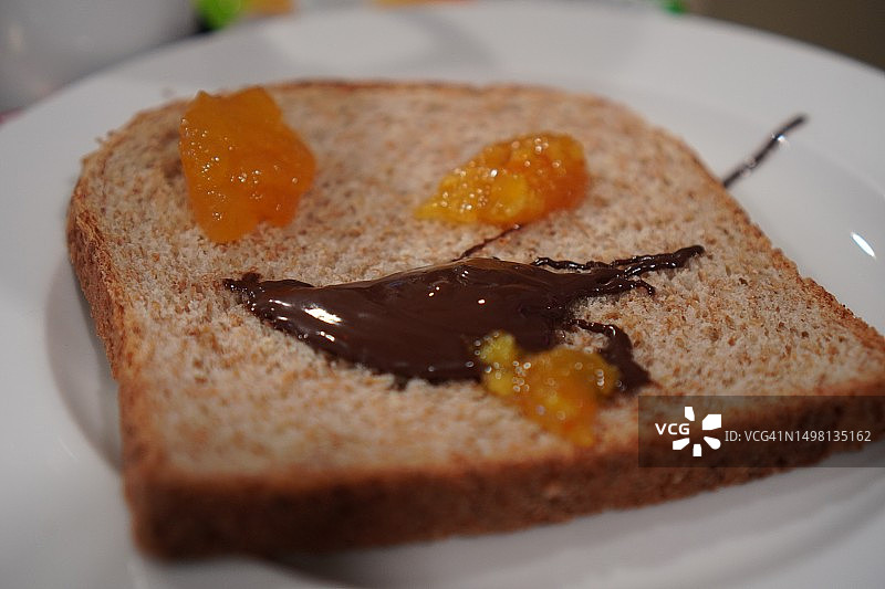 白色盘子上搭配巧克力和橙子酱的切片面包早餐图片素材