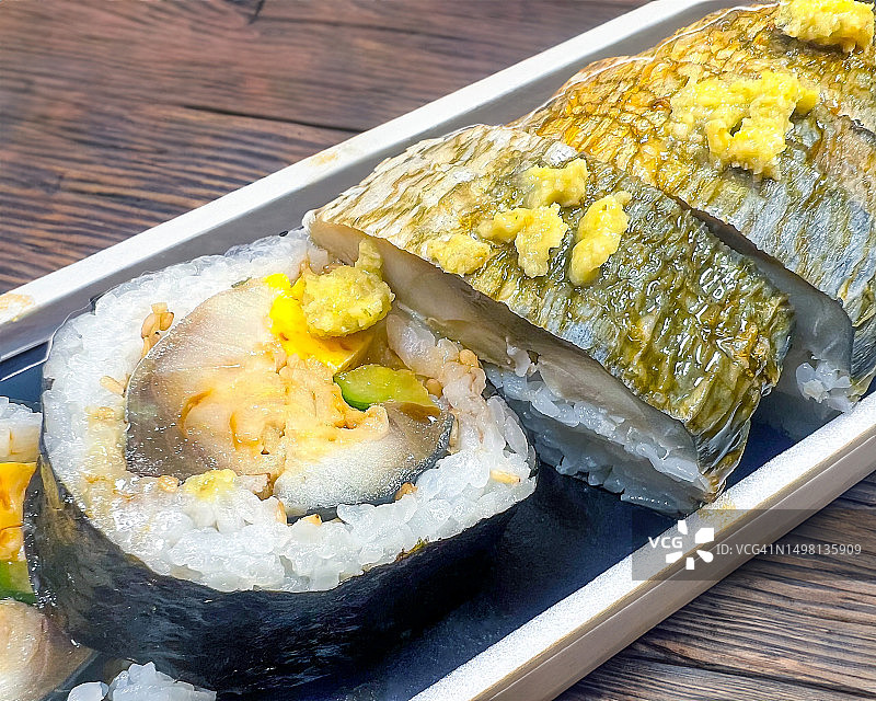 北海道鲭鱼寿司和太卷，一次性塑料盒盛装，置于木桌上图片素材