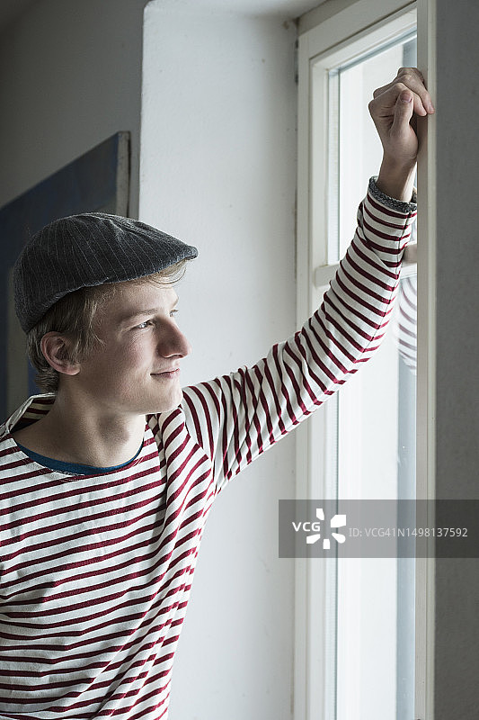 微笑并透过窗户看的年轻男子，巴伐利亚，德国图片素材