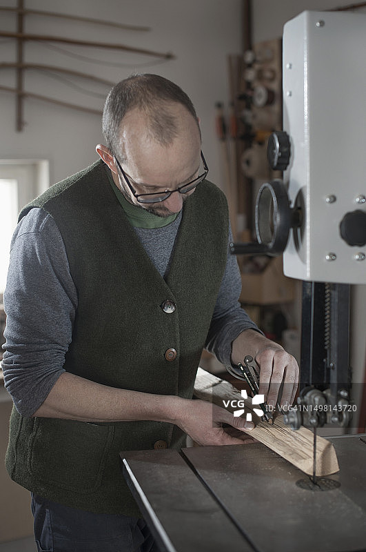 男人在巴伐利亚的工作室里用圆规在木头上做标记图片素材