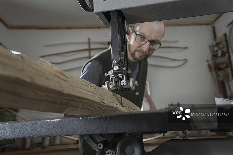 在德国巴伐利亚，男性弓箭制造者用带锯锯木头图片素材