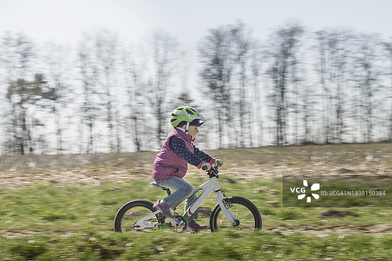 小女孩在田野里骑自行车图片素材