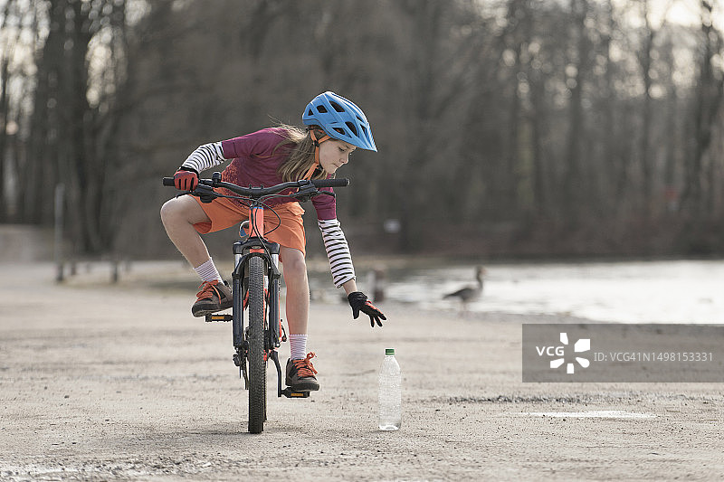 德国巴伐利亚女性山地自行车手训练时捡起水瓶图片素材