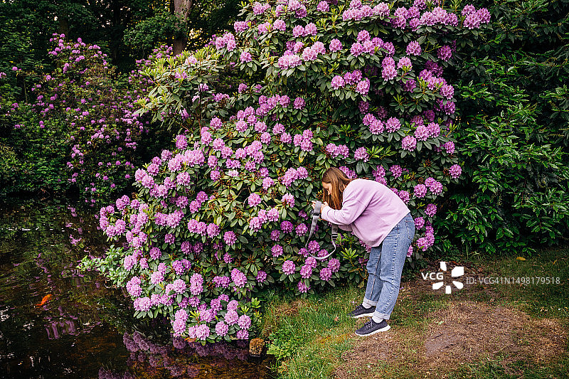 年轻女子用单反相机拍摄自然风光图片素材