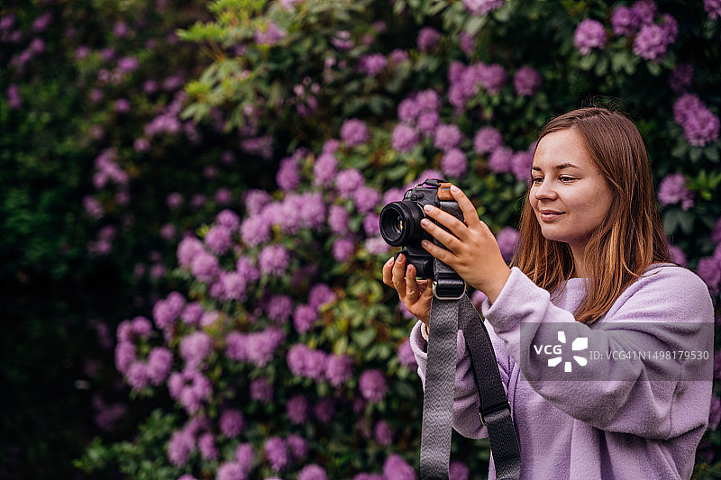 使用单反相机拍照的微笑年轻女性肖像图片素材