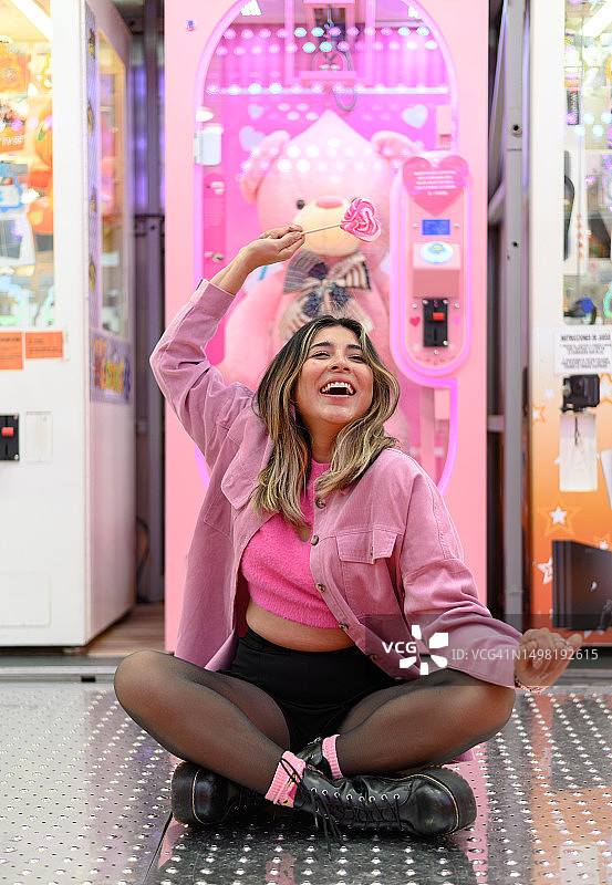 女人在集市里坐着跳舞，手里拿着棒棒糖图片素材