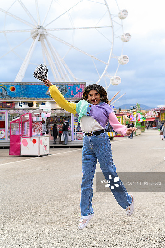 穿着彩色服装在集市上跳跃的快乐女人图片素材