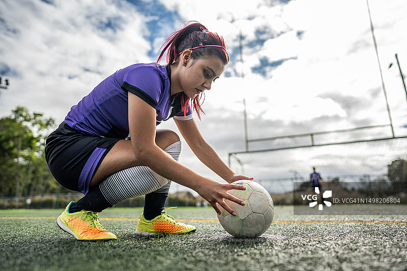 年轻女人准备在足球场踢点球图片素材