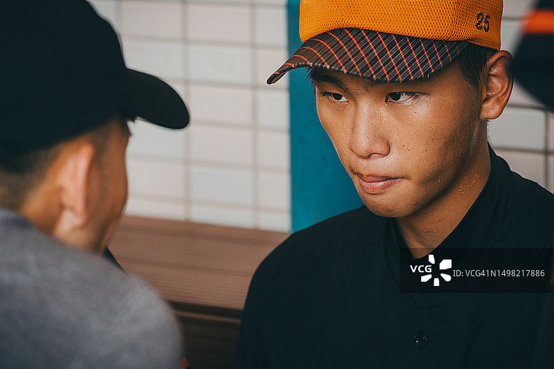 职业棒球比赛中，运动教练在休息区与投手交谈，帮助他建立心理建设图片素材