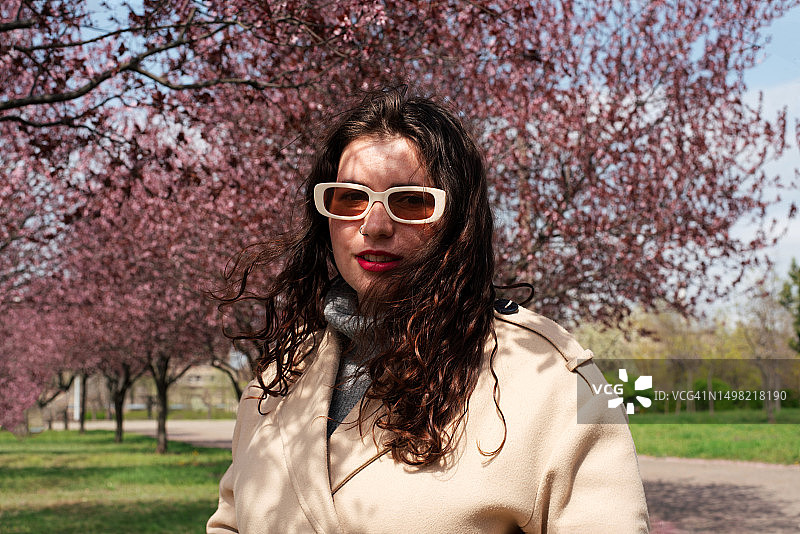 年轻女子站在盛开的玫瑰树下。平衡。与自然重新连接。和谐。心理平衡。图片素材