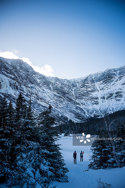 两个男人站在冰冻的湖边看山图片素材