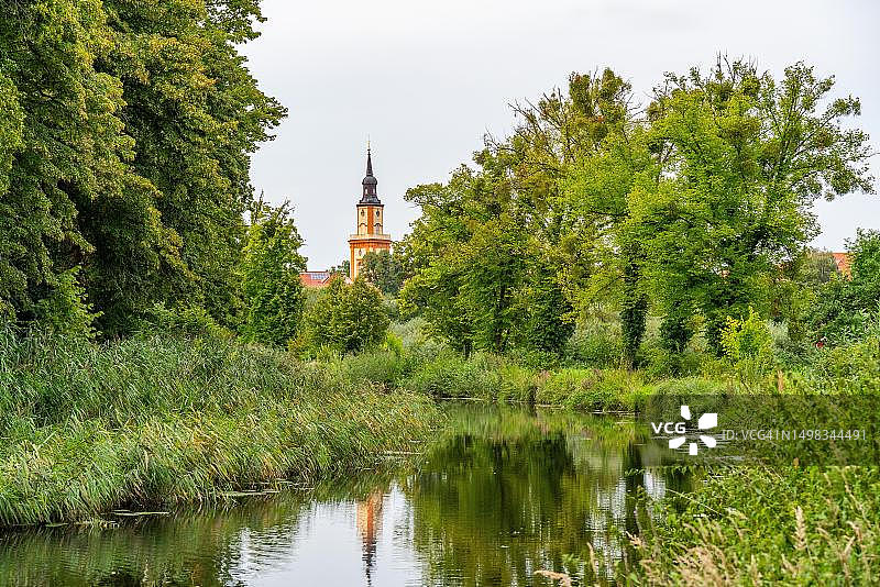 滕普林运河沿岸的绿色景观，背景是圣玛丽马格达莱纳教堂，德国勃兰登堡州乌克马克图片素材