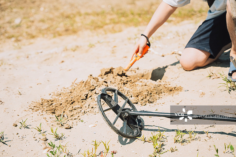 男子用手持金属探测器在沙滩上寻找珠宝图片素材