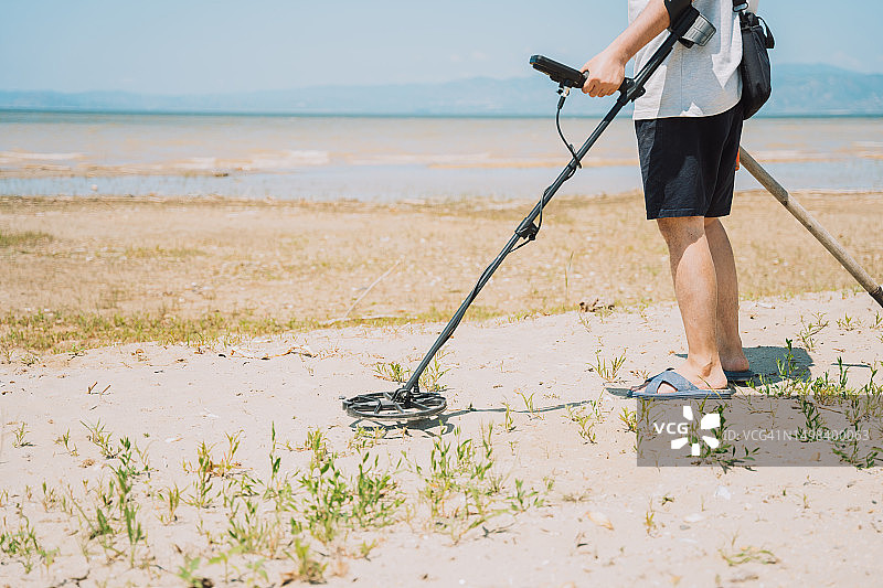 在海滩上用金属探测器寻找珠宝的男人图片素材