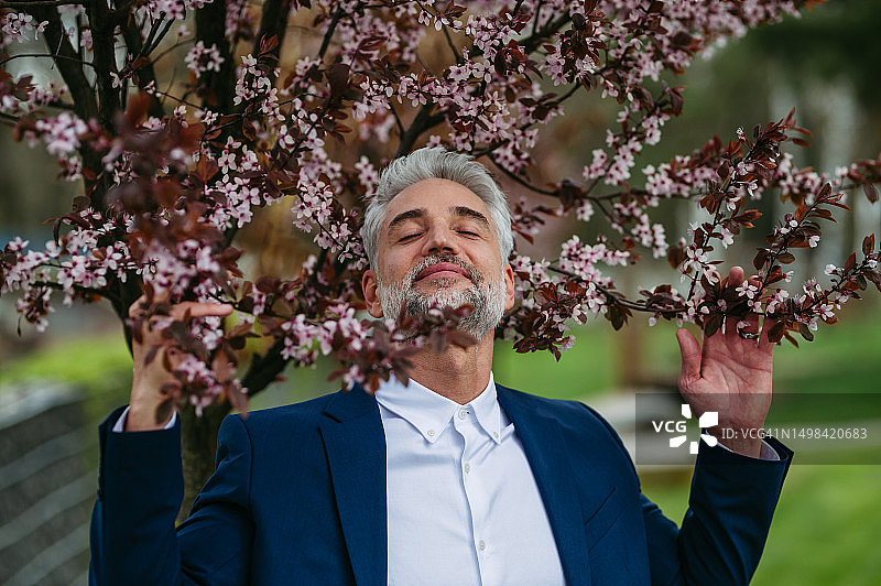 商人在花园里闻树上的花图片素材