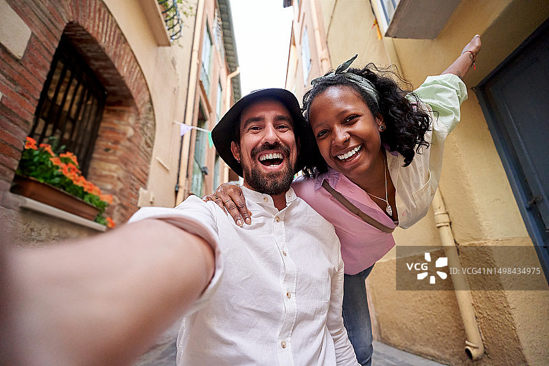 幸福的多元文化情侣在海边村庄自拍图片素材