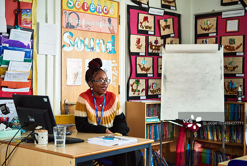 中年女教师在课堂上坐在桌旁微笑图片素材