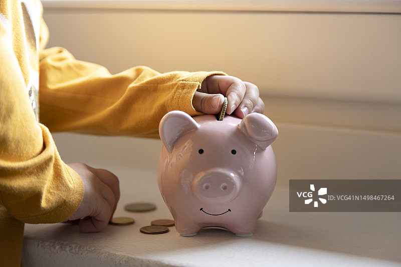 男孩在存钱罐里存钱图片素材