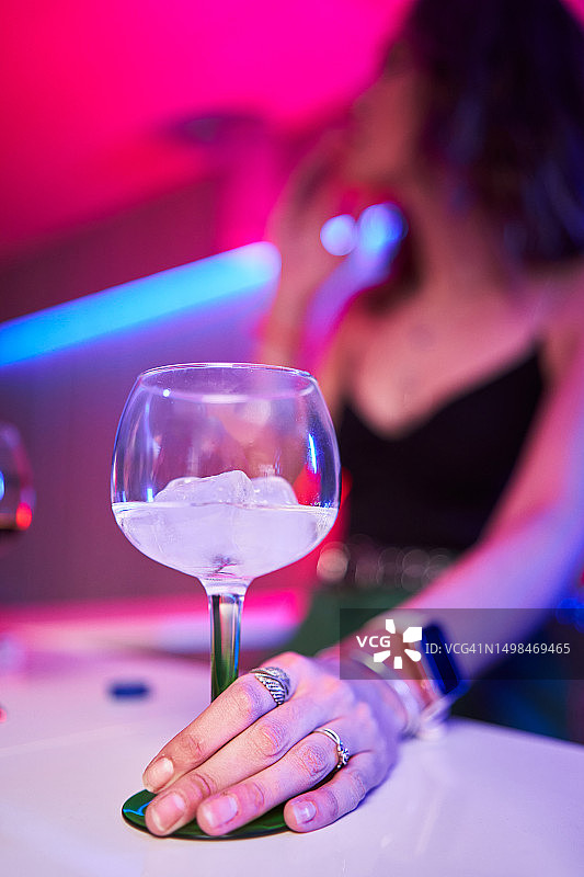 在迪斯科舞厅里拿着一杯冰镇鸡尾酒的调酒师图片素材