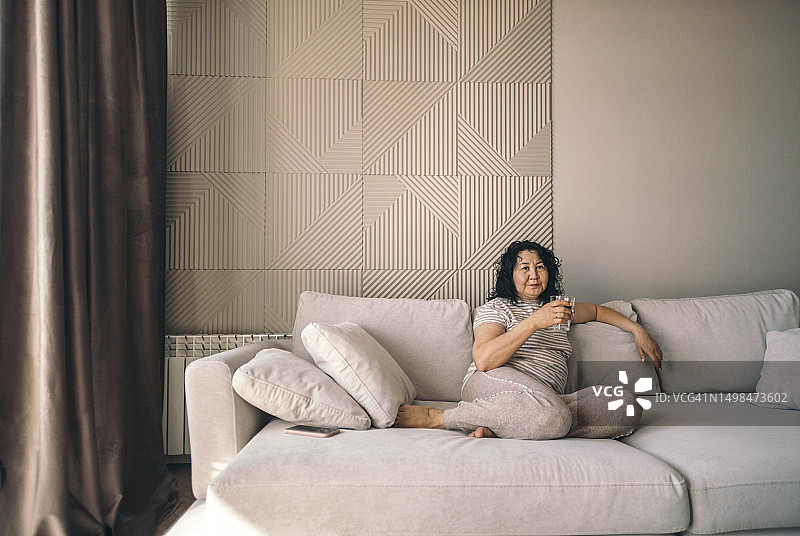 女人在家中沙发上拿着一杯水图片素材