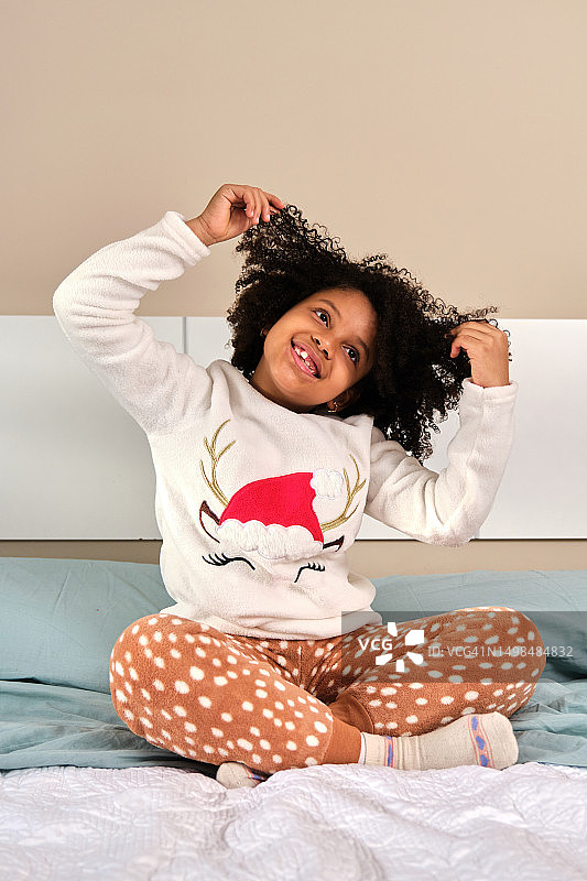 穿着睡衣坐在床上的快乐女孩图片素材