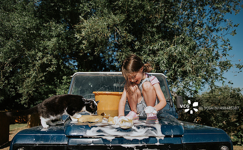 小女孩和宠物猫一起清洗老爷车图片素材