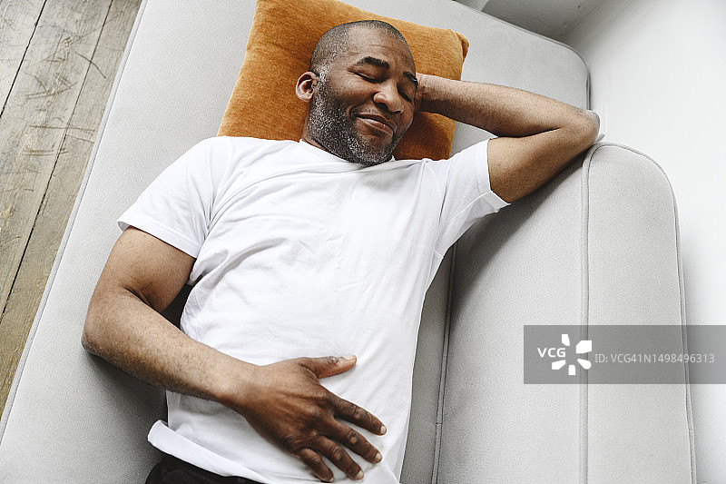 在家里的沙发上睡觉的中年男人图片素材