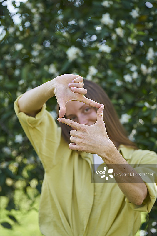 女子在花园里用手指做框架图片素材
