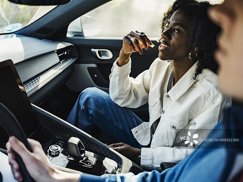 女子在车里和朋友一起吃糖果图片素材